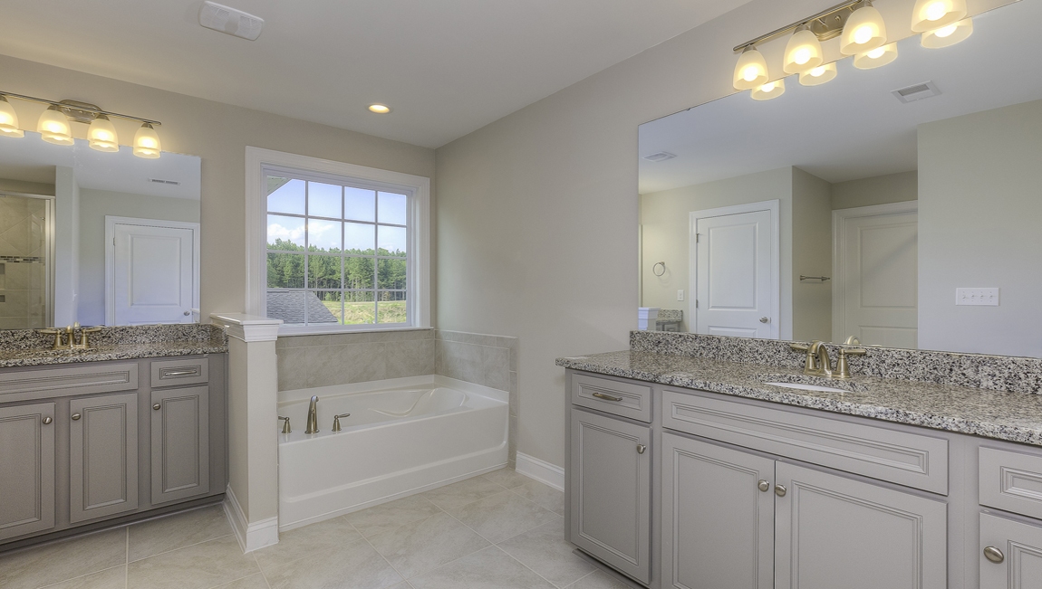 Primary bathroom with white cabinets, double sinks, and separate bathtub and standing glass door shower