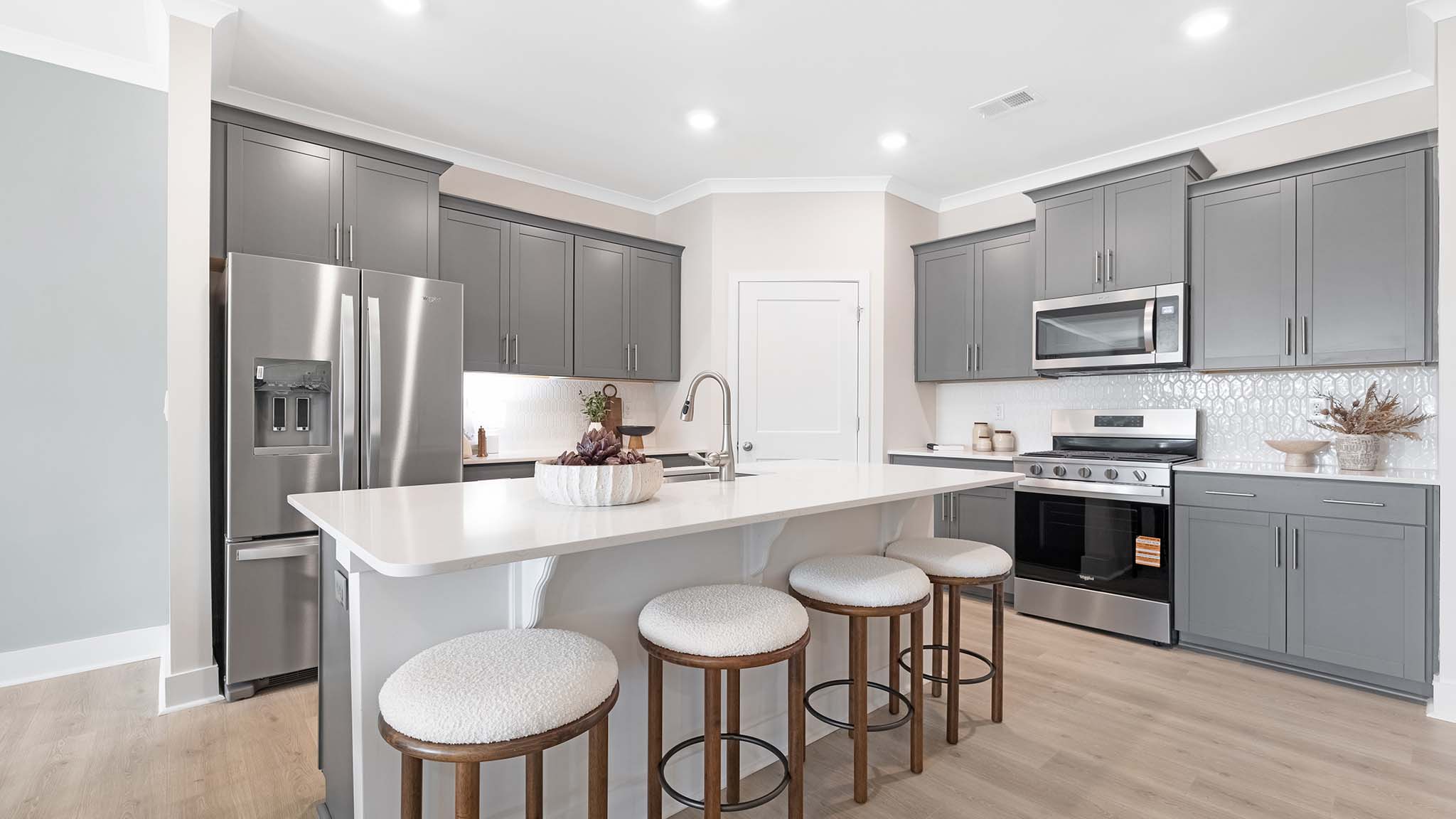 Kitchen and island with white cabinets and stainless steel appliances
