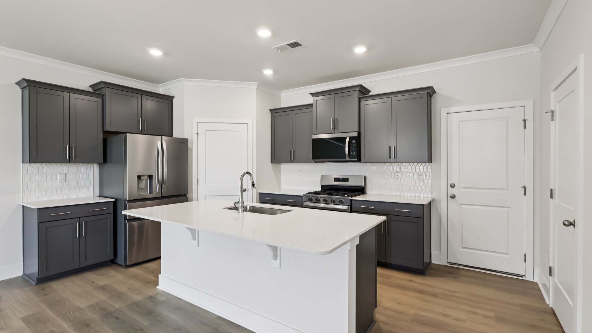 Kitchen and island with white cabinets and stainless steel appliances