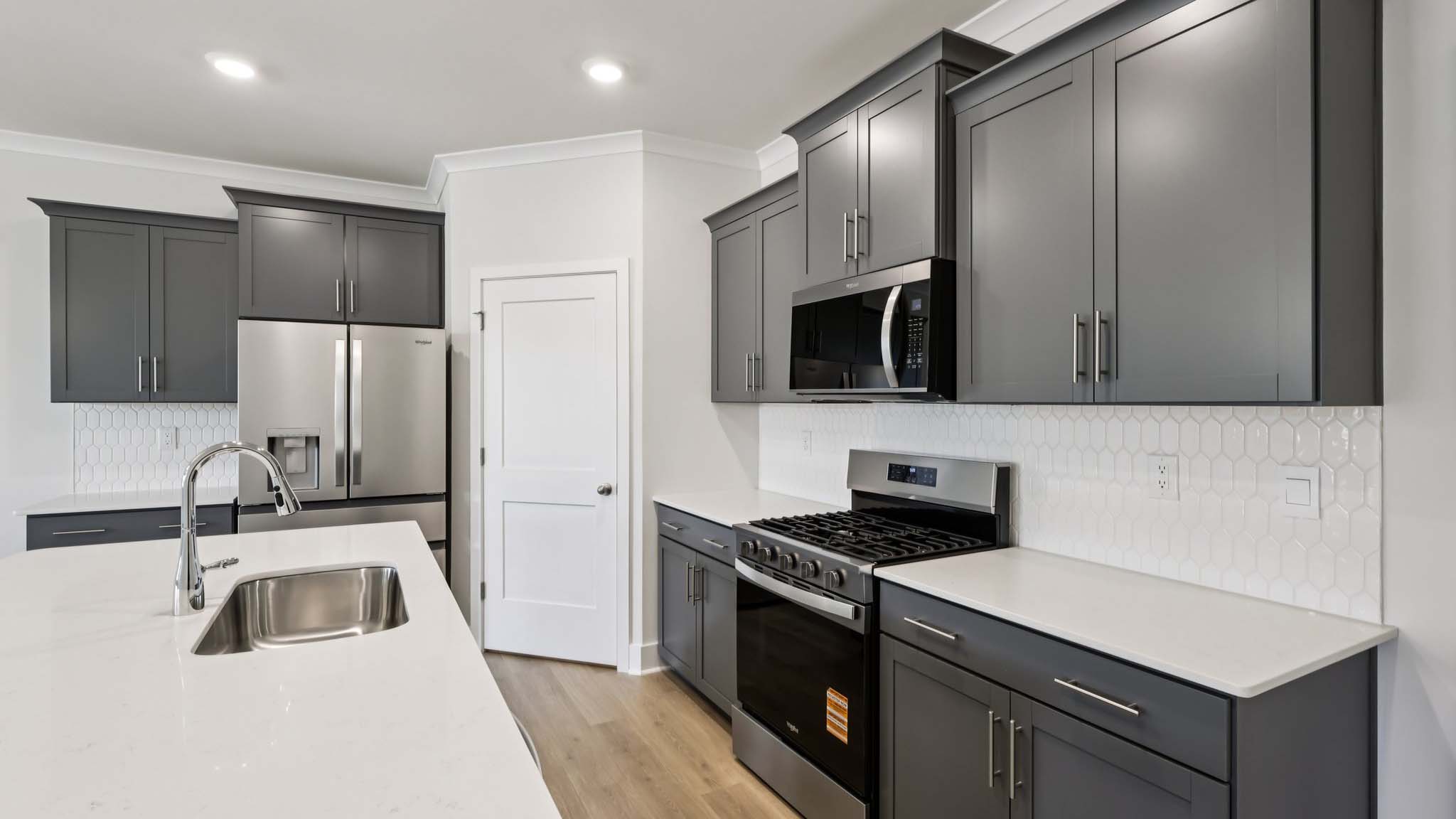 Kitchen and island with white cabinets and stainless steel appliances