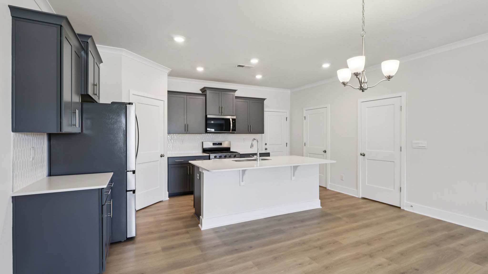 Kitchen and island with white cabinets and stainless steel appliances