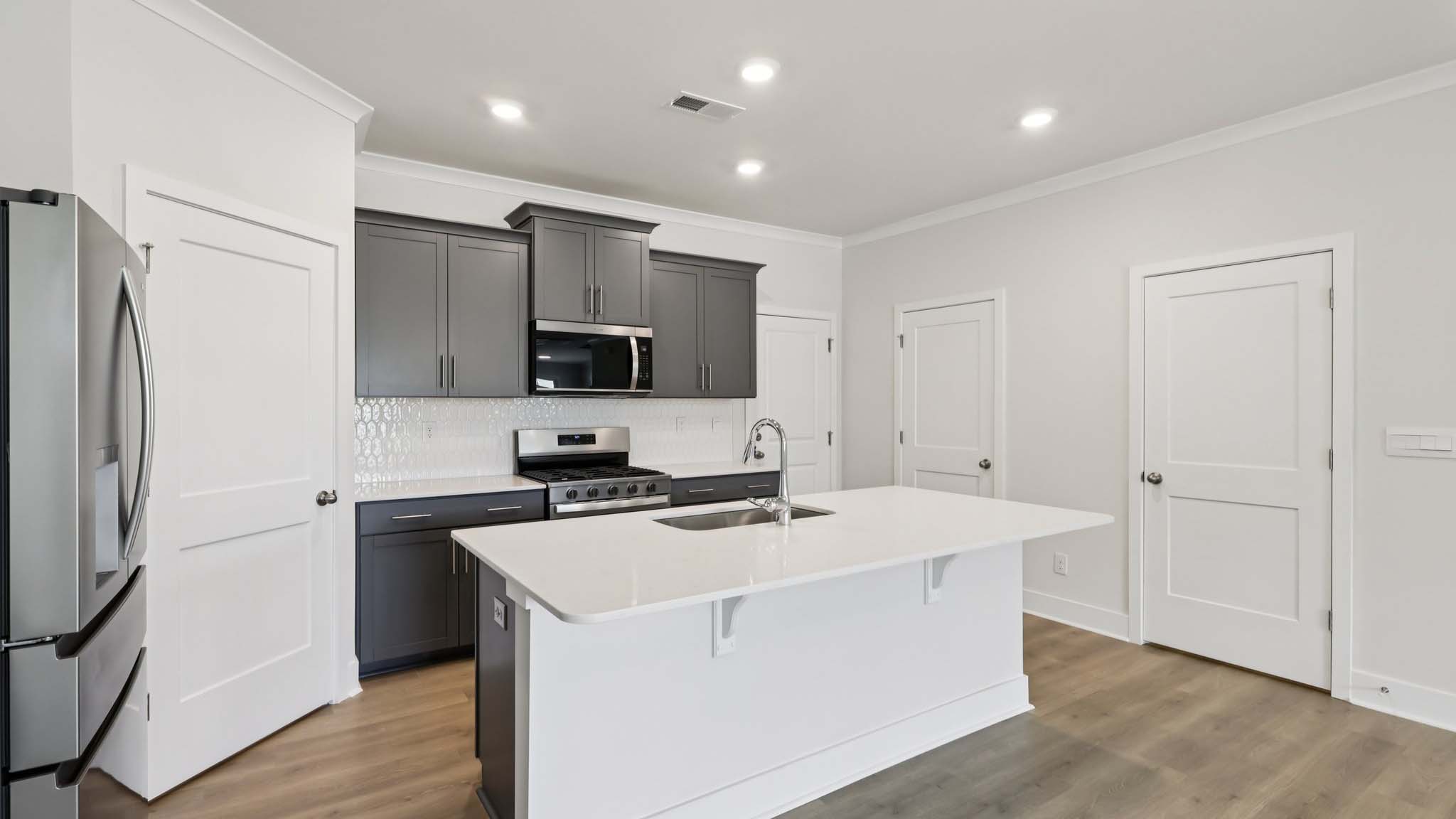 Kitchen and island with white cabinets and stainless steel appliances