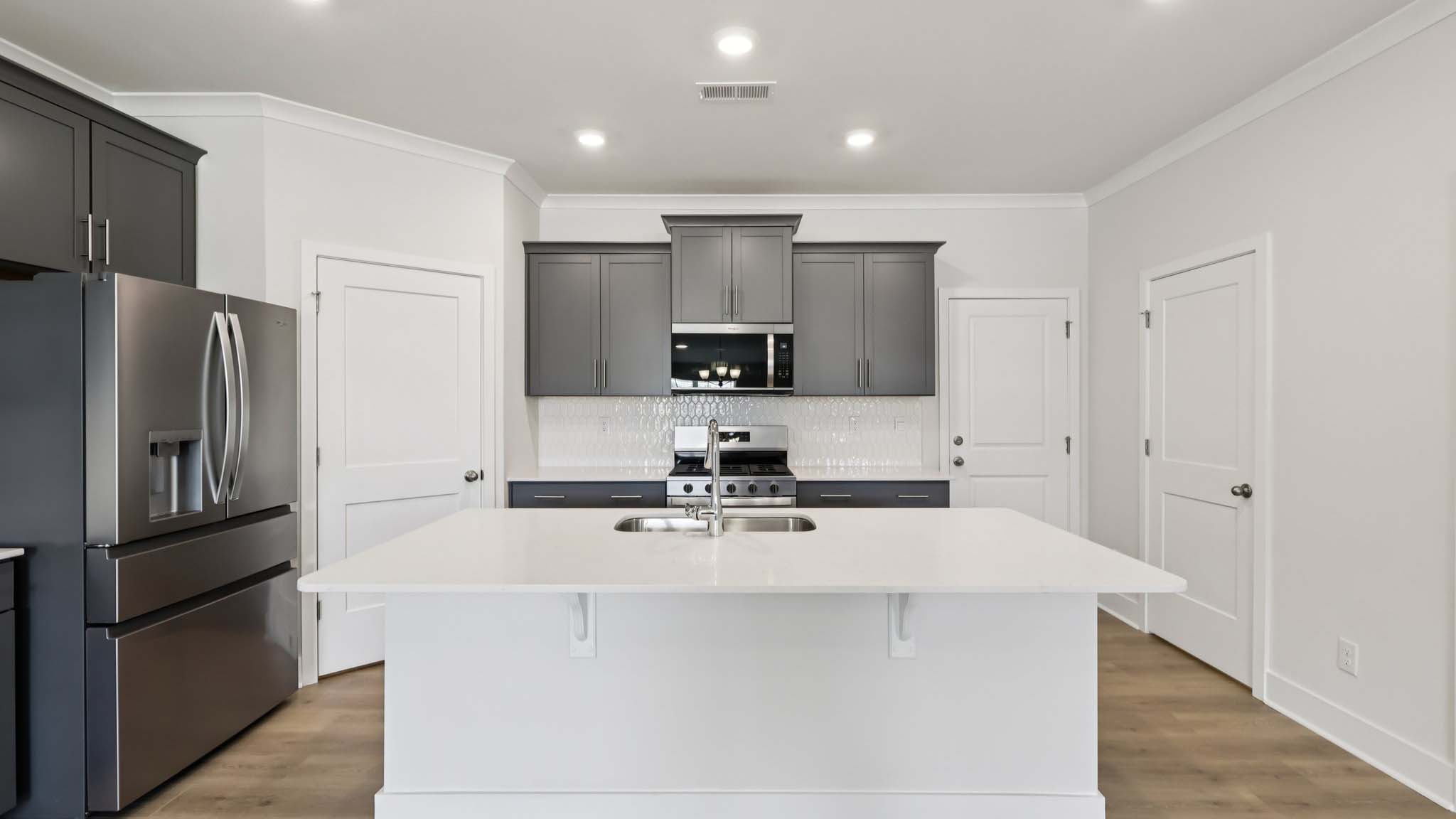 Kitchen and island with white cabinets and stainless steel appliances