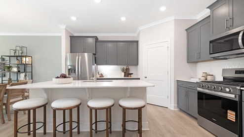 Kitchen and island with white cabinets and stainless steel appliances