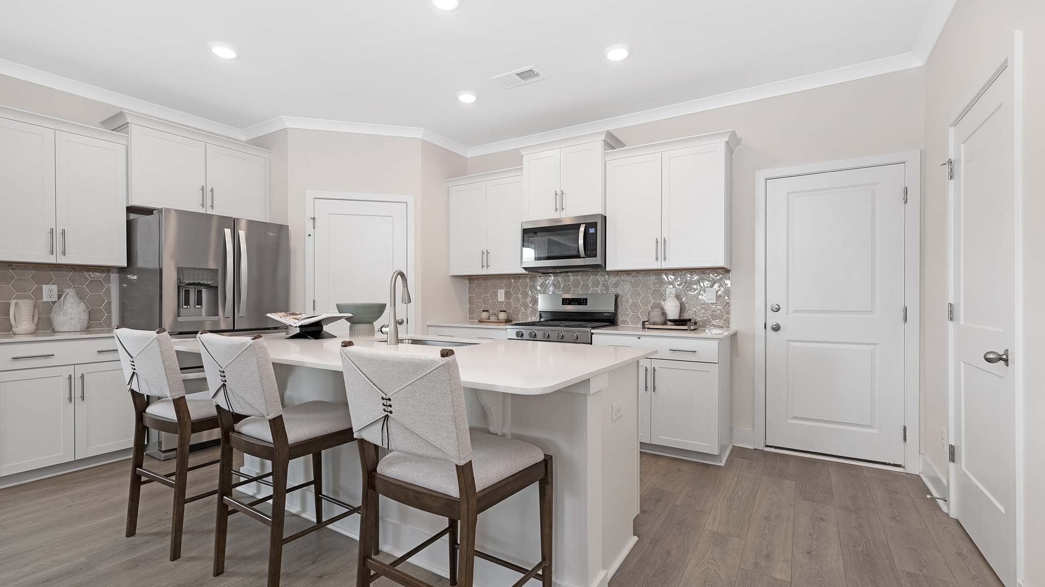 Kitchen and island with white cabinets and stainless steel appliances
