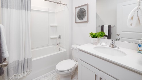 Bathroom with white counters and cabinets, and bathtub and shower combination
