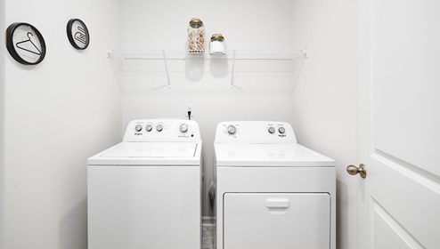 Laundry room with storage and hanging racks above machines