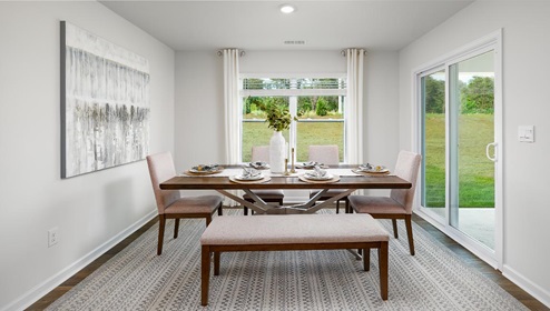 Dining area beside kitchen and living room with large windows and sliding glass back door
