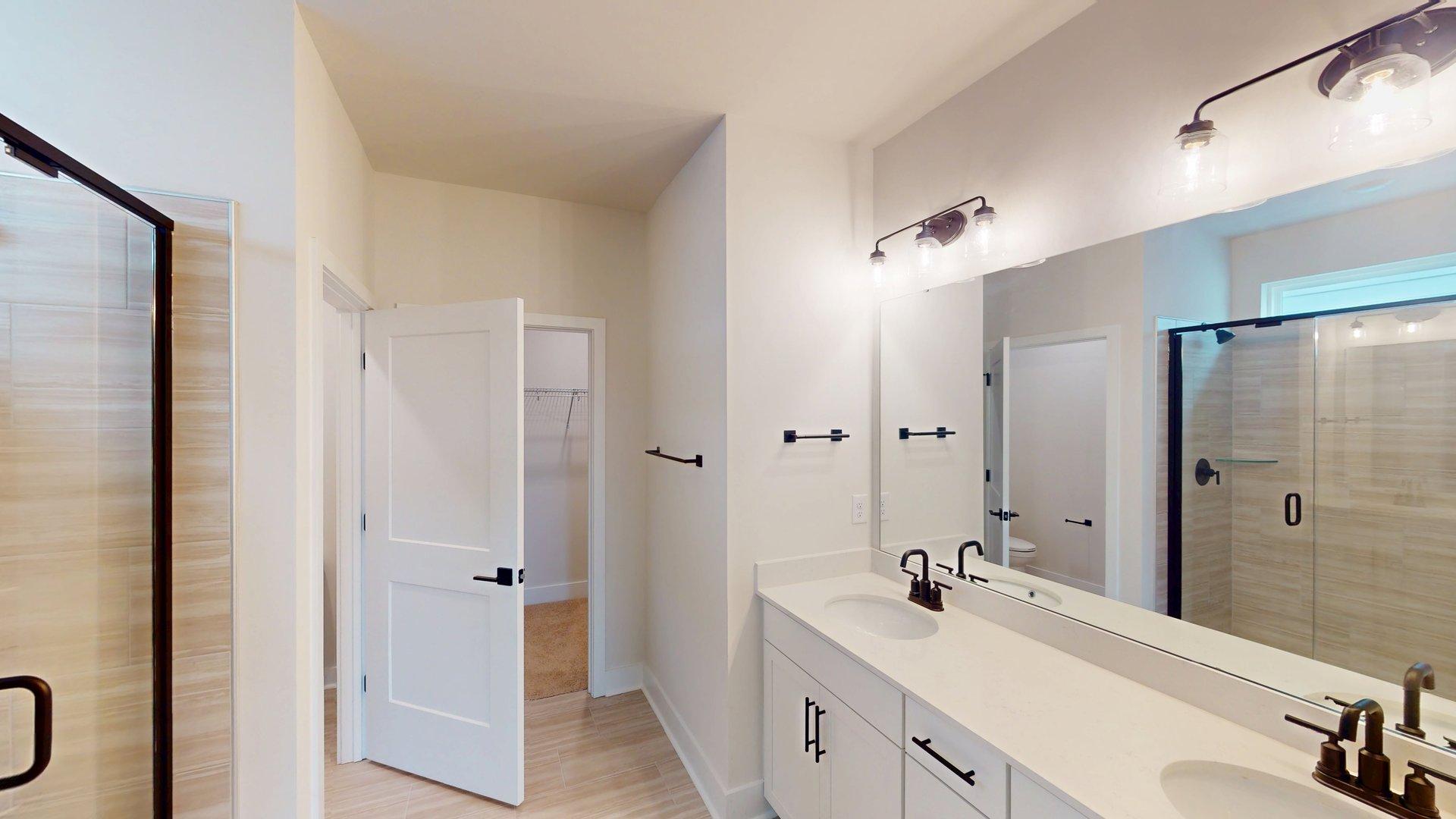 Primary bathroom with double sink vanity, large standing shower, and accessibility to primary bedroom and closet