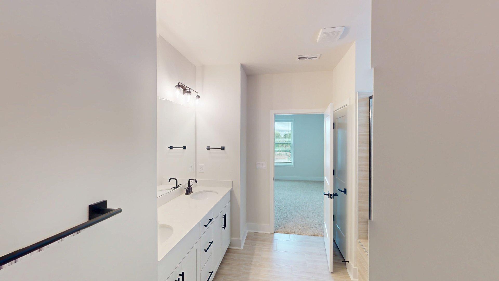 Primary bathroom with double sink vanity, large standing shower, and accessibility to primary bedroom and closet