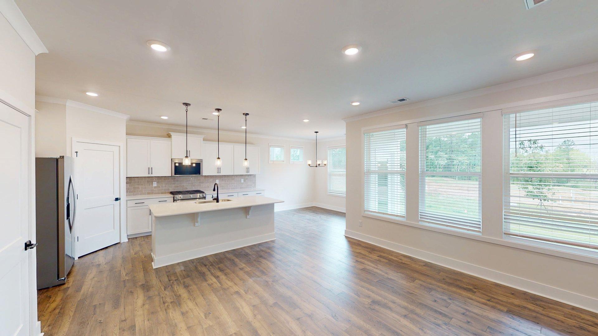 kitchen and island with large windows, white cabinets and stainless steel appliances