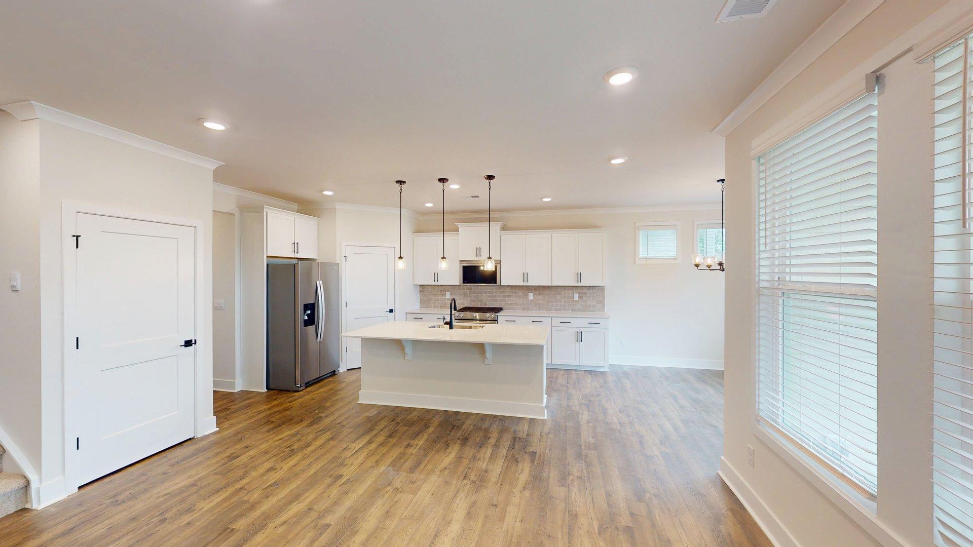 kitchen and island with large windows, white cabinets and stainless steel appliances