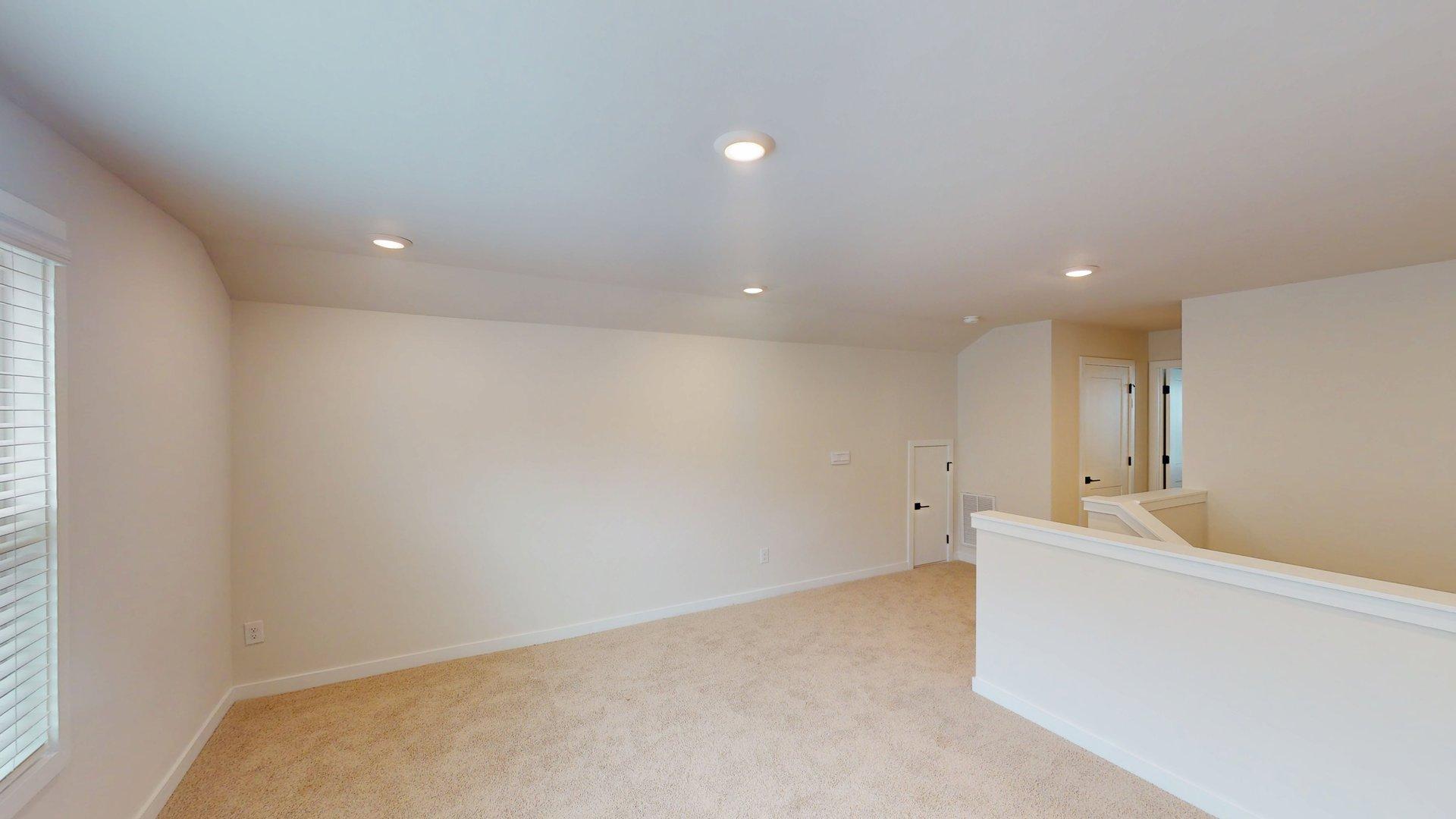 carpeted upstairs loft space with large windows