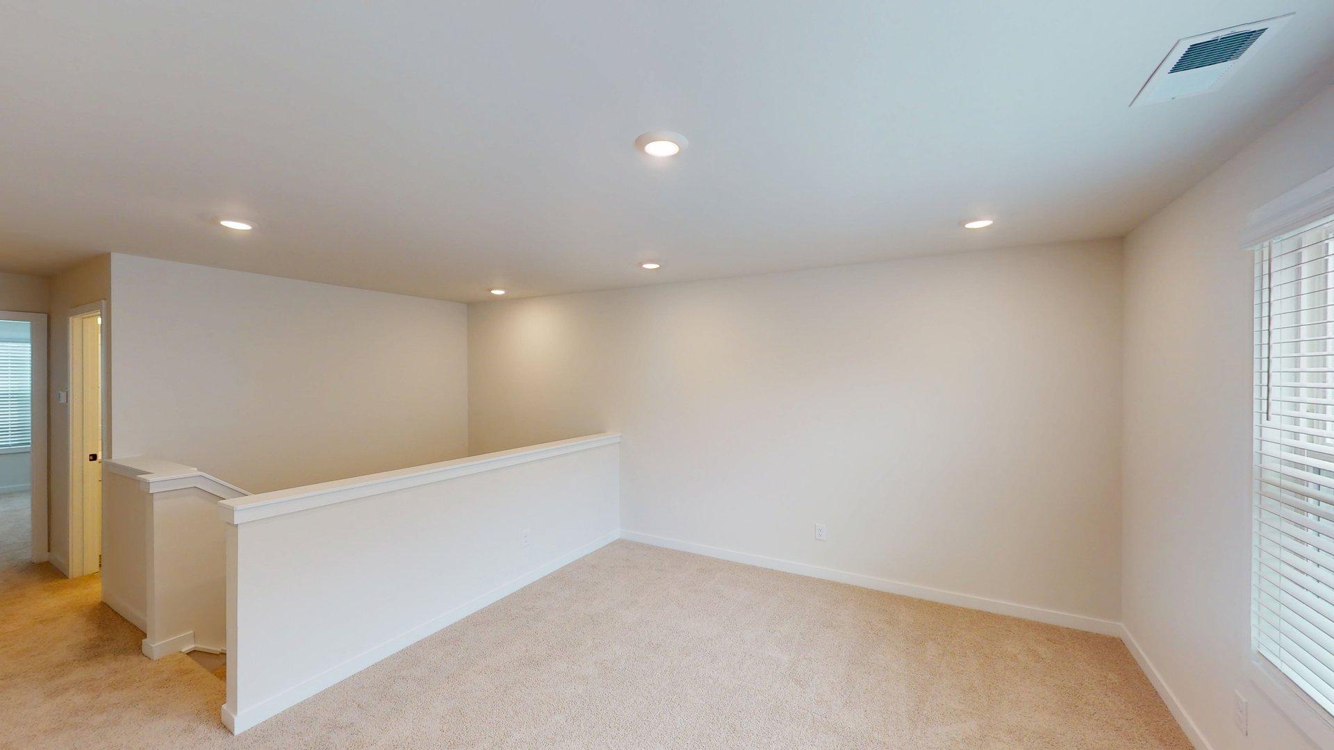 carpeted upstairs loft space with large windows