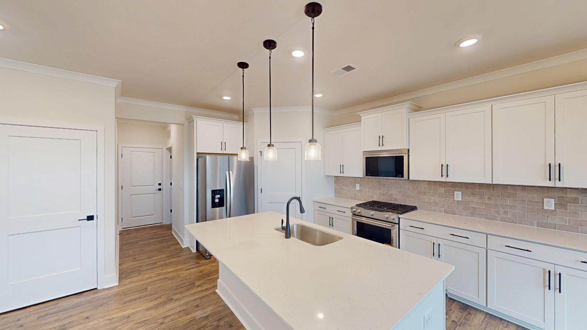kitchen and island with large windows, white cabinets and stainless steel appliances