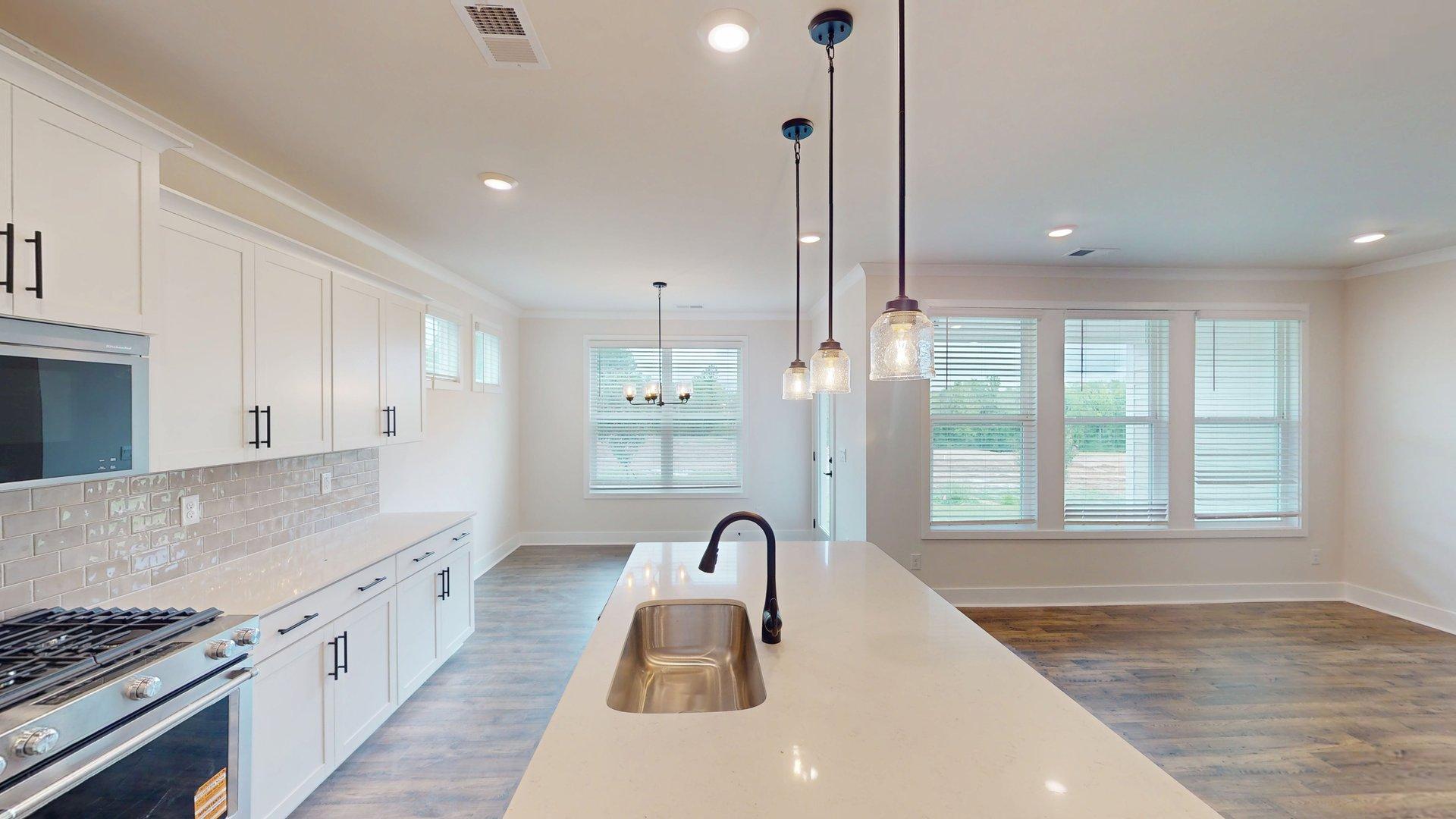 kitchen and island with large windows, white cabinets and stainless steel appliances