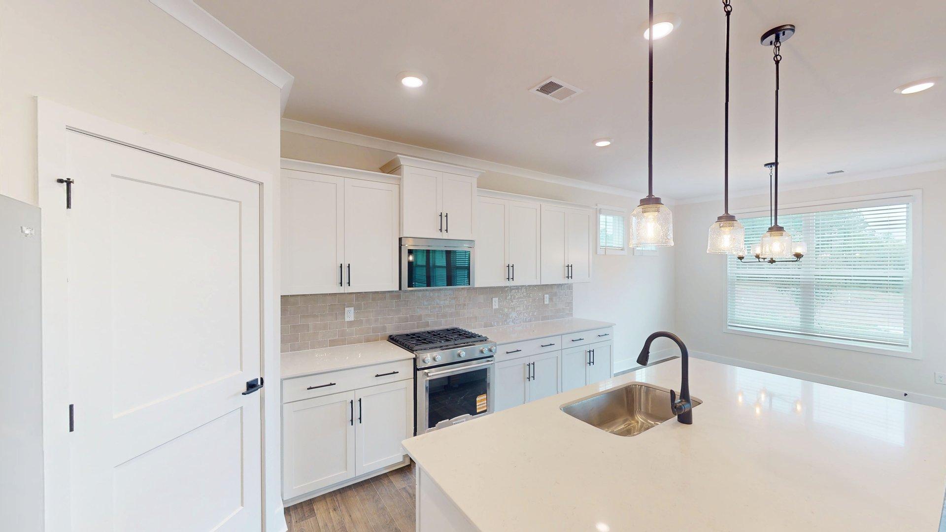 kitchen and island with large windows, white cabinets and stainless steel appliances