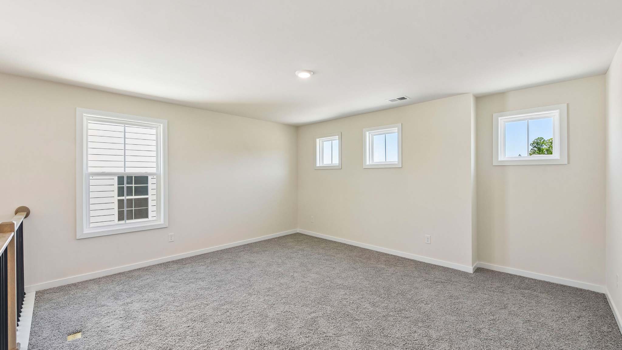 Carpeted upstairs loft area with windows