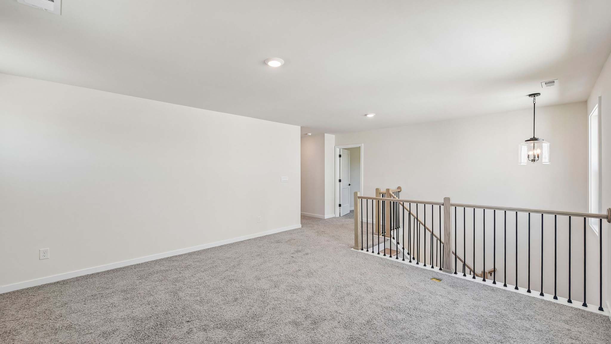 Carpeted upstairs loft area with windows