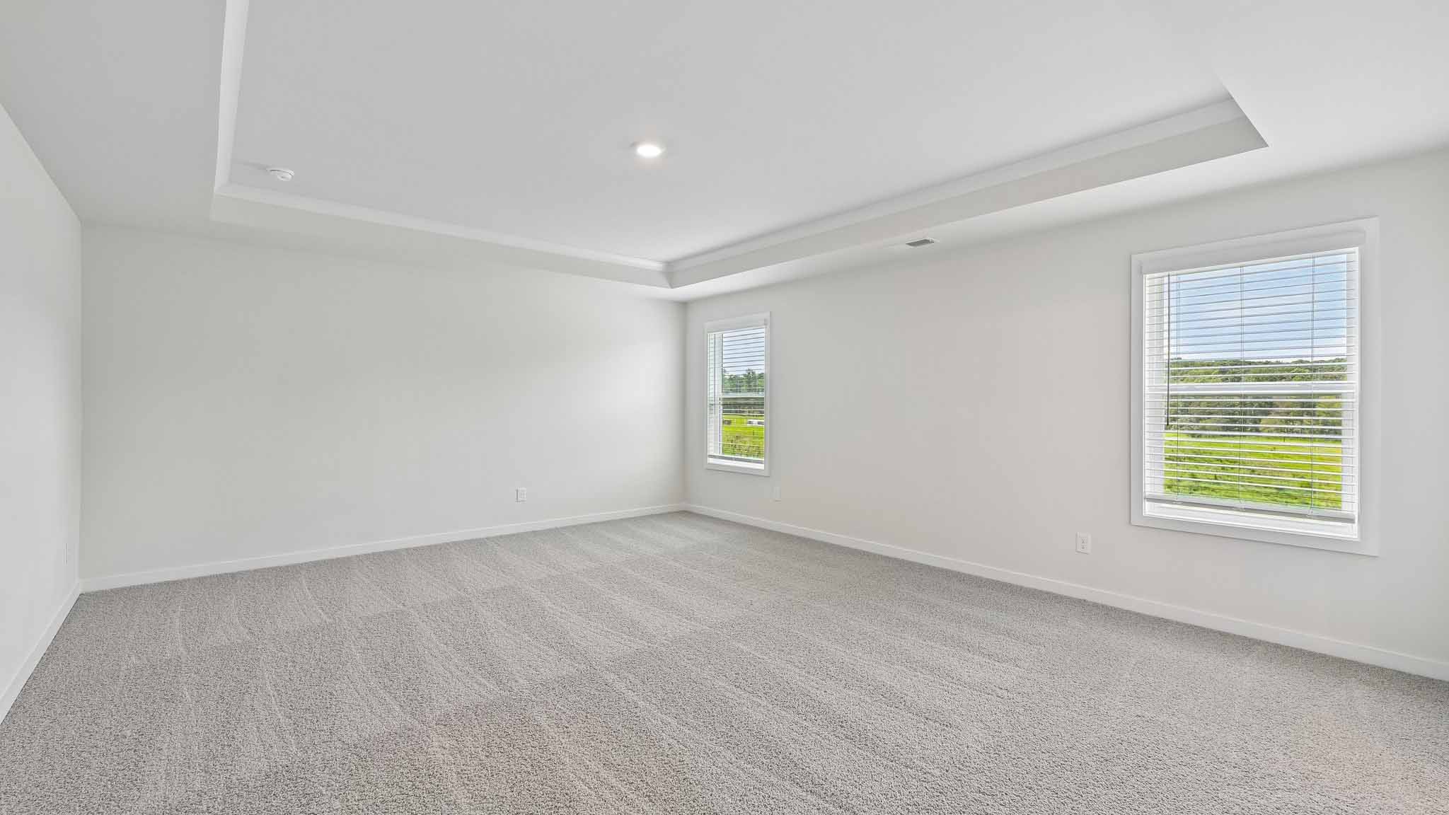 Primary carpeted bedroom with windows