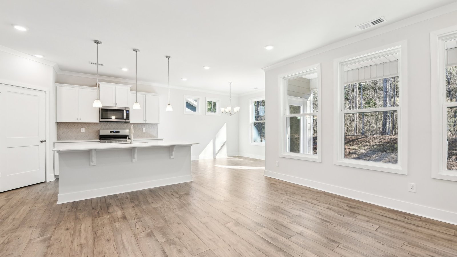 Kitchen and island with white cabinets, tile backsplash, quartz countertops, and stainless steel appliances