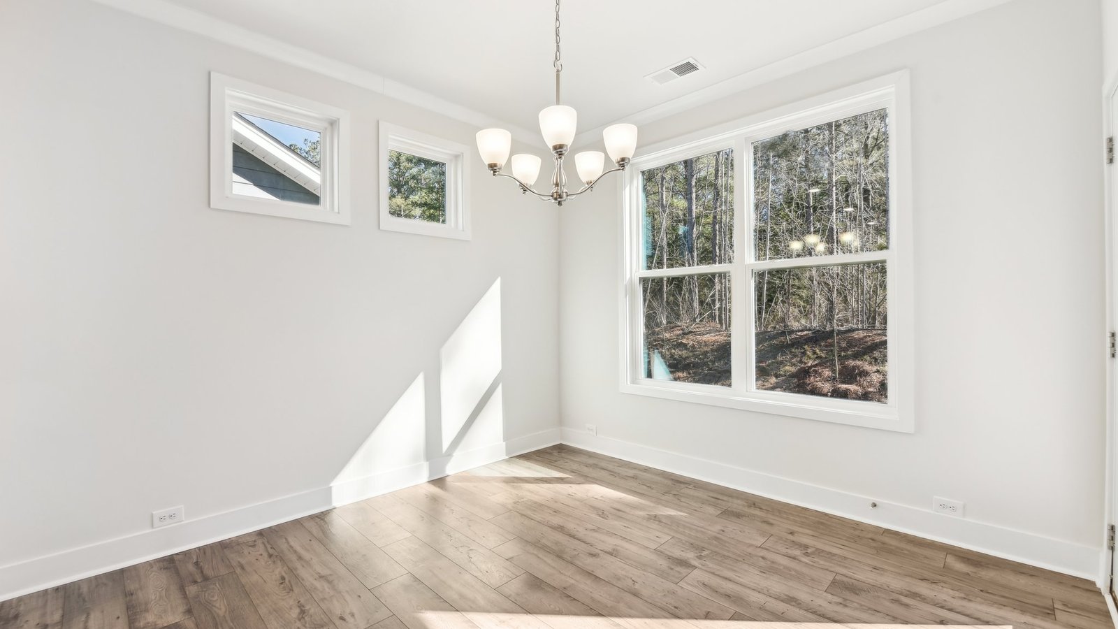 Dining area beside kitchen with chandelier and large window