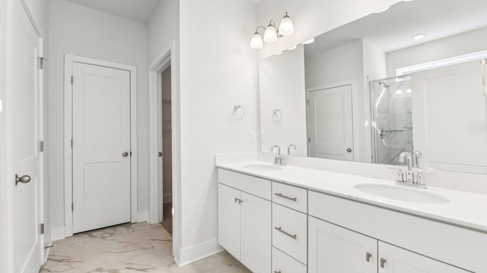 Primary bathroom  with double sink vanity, white counters and cabinets, and standing glass door shower
