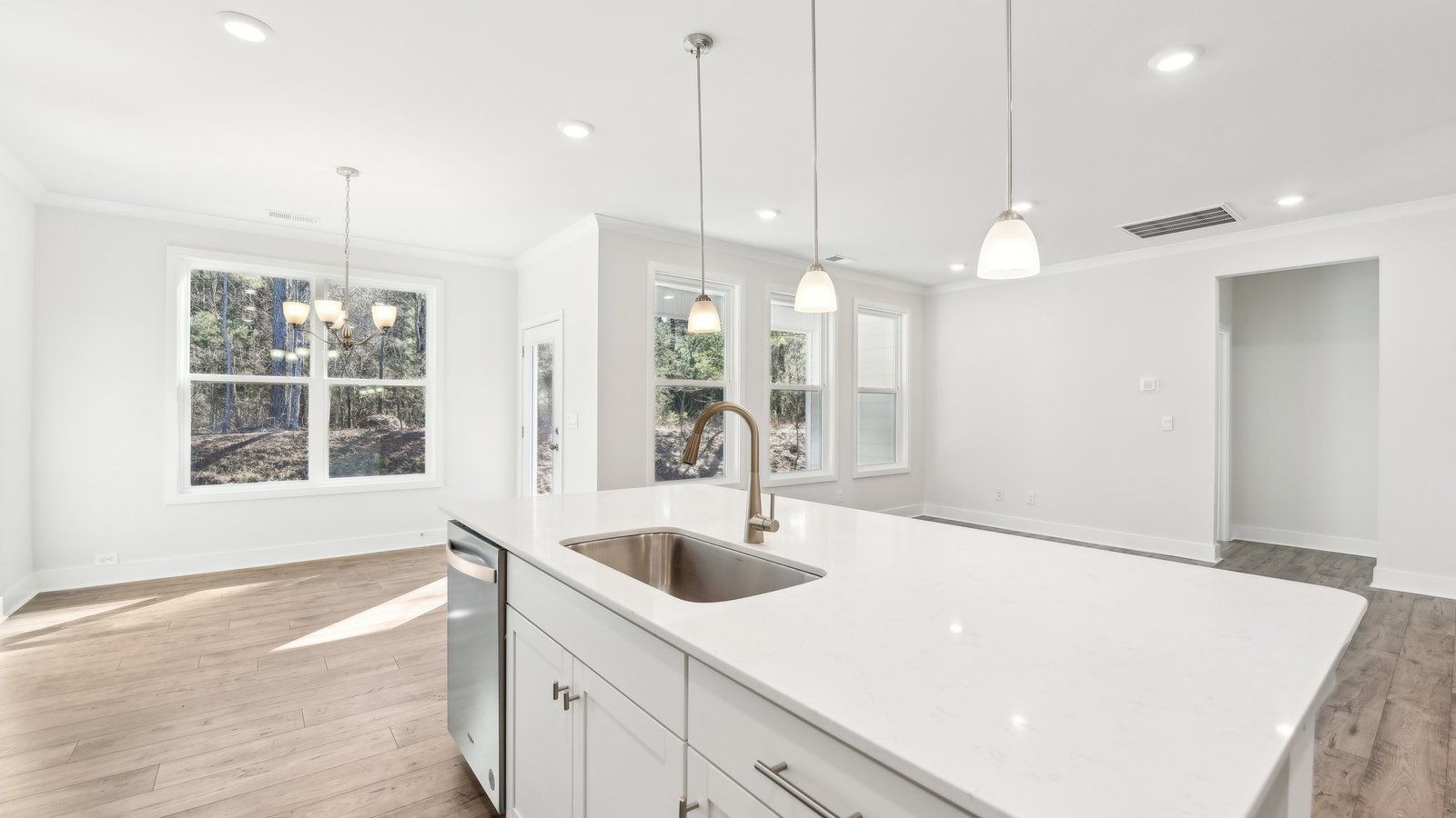 Kitchen and island with white cabinets, tile backsplash, quartz countertops, and stainless steel appliances