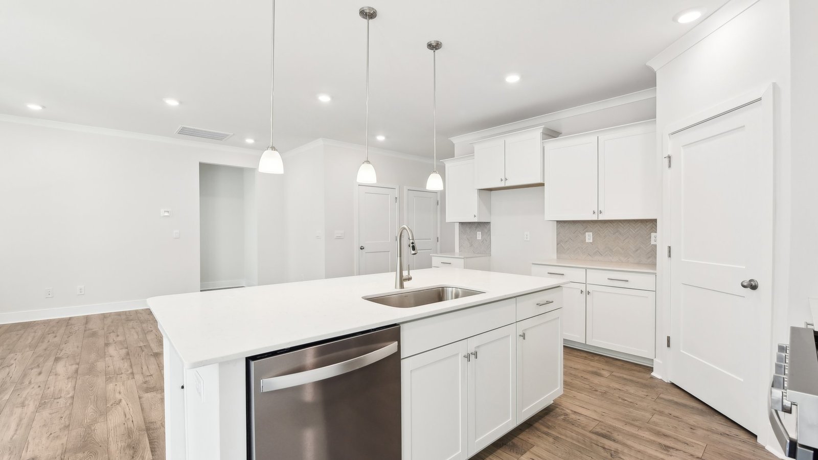 Kitchen and island with white cabinets, tile backsplash, quartz countertops, and stainless steel appliances