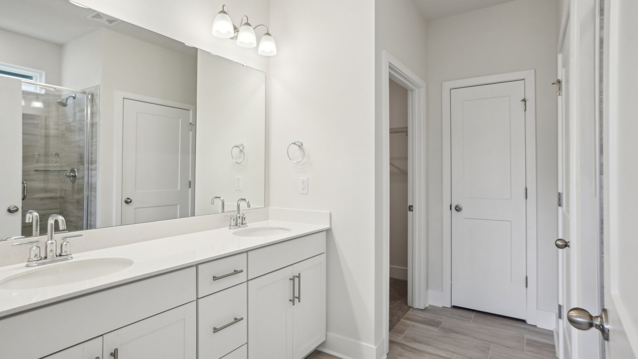 Primary bathroom  with double sink vanity, white counters and cabinets, and standing glass door shower
