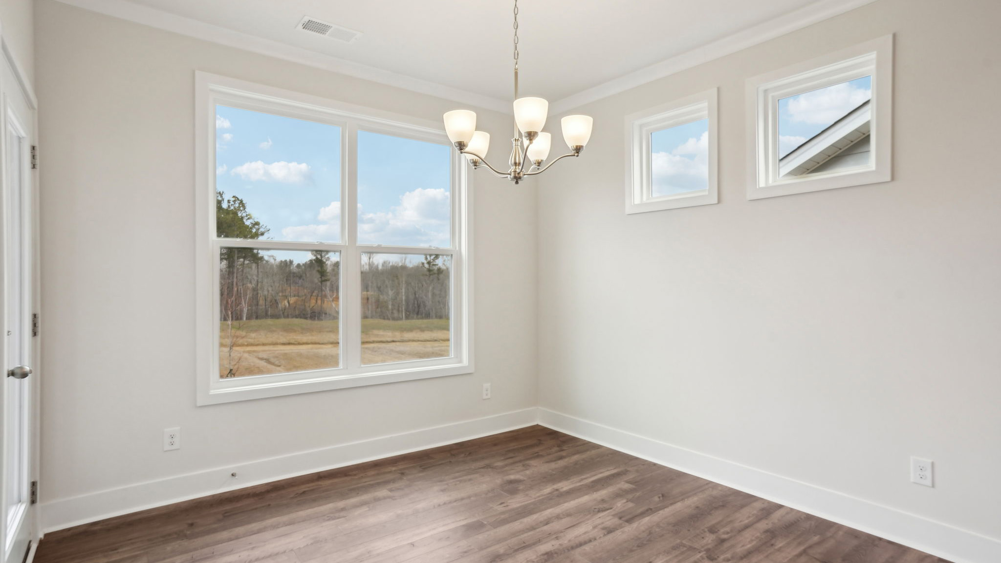 Dining area beside kitchen with chandelier and large window
