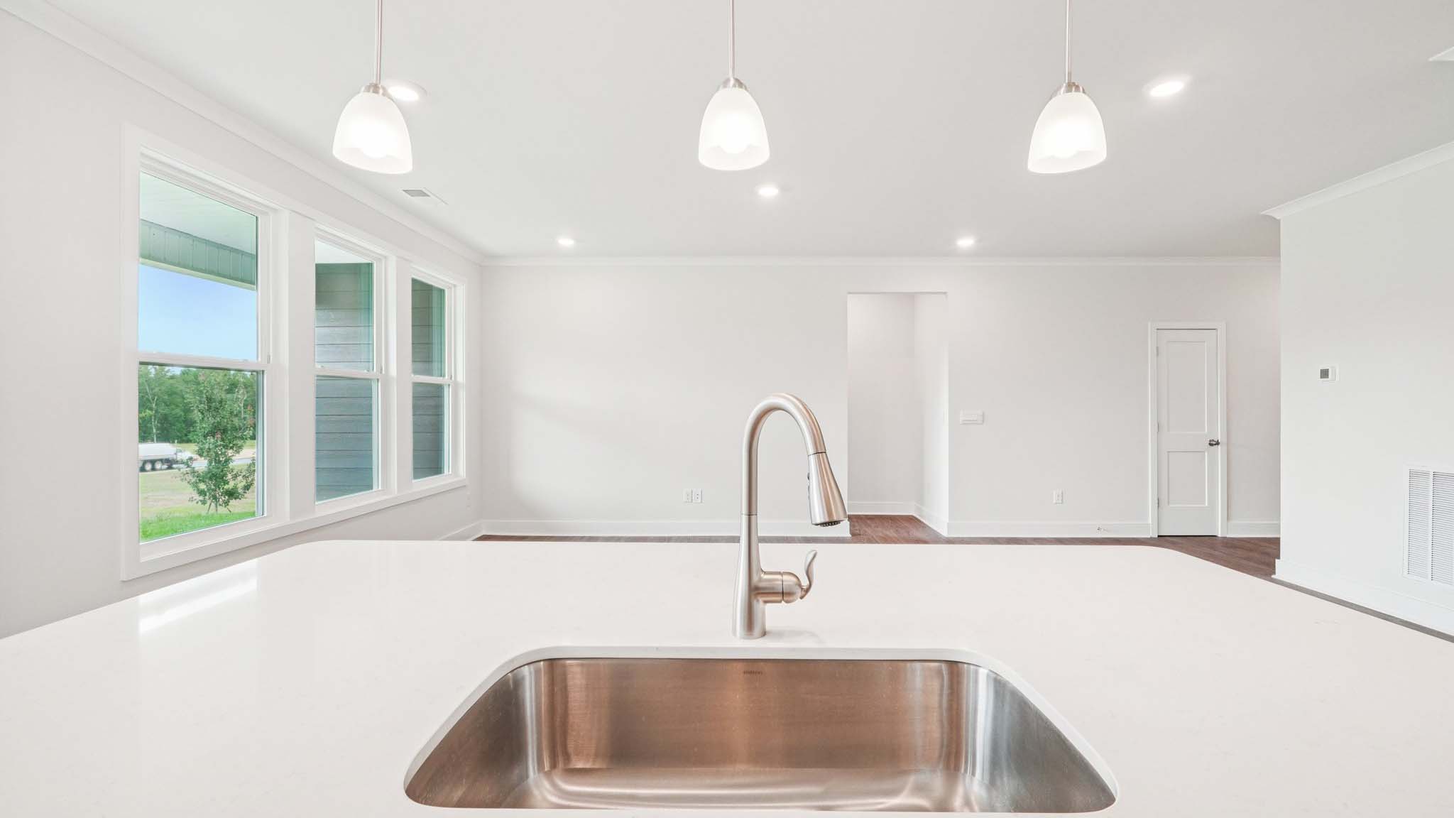 Kitchen and island with white cabinets, stainless steel appliances and hanging lights