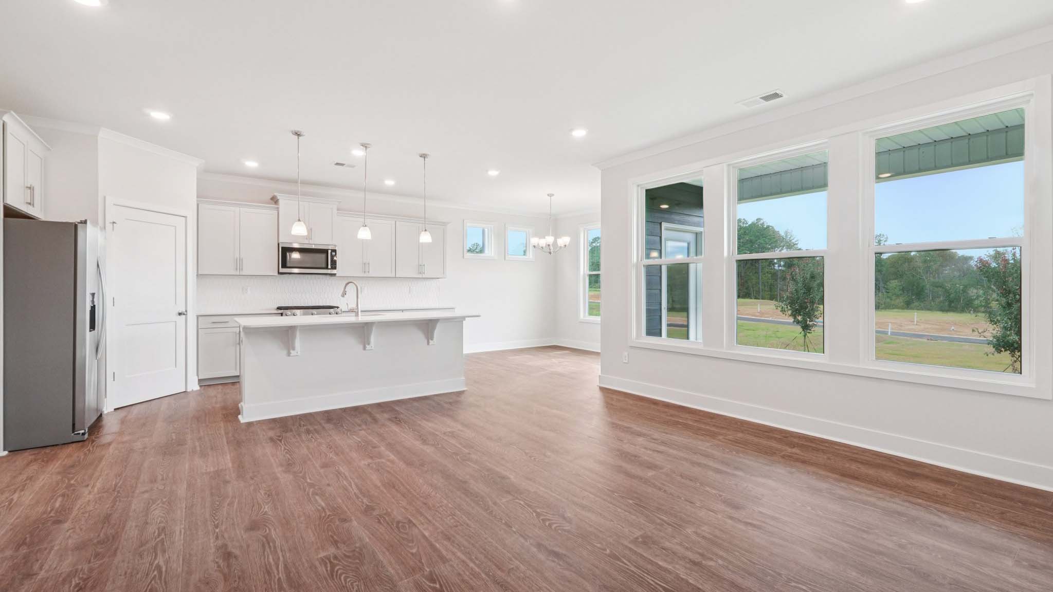Open concept living room beside kitchen with large windows