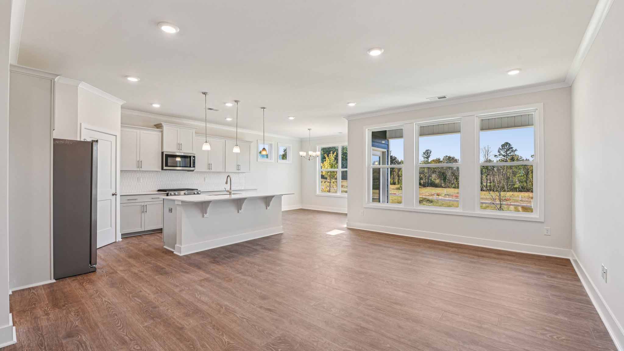 Open concept living room beside kitchen with large windows