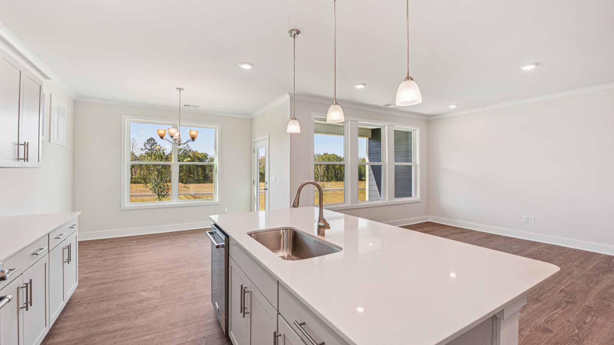 Kitchen and island with white cabinets, stainless steel appliances and hanging lights
