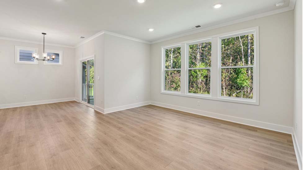 Living room with three large windows, beside dining area