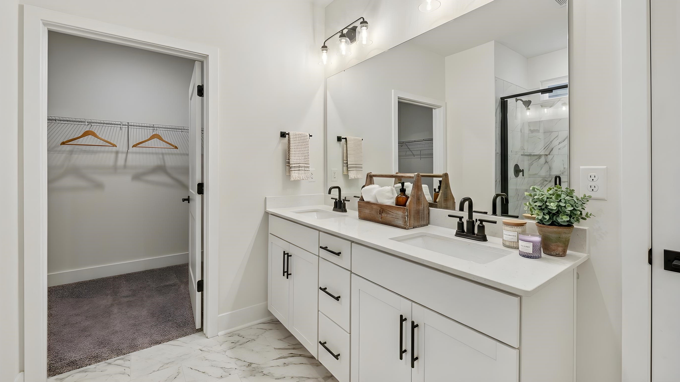 Primary bathroom with double sink vanity, large shower, and attached walk in closet