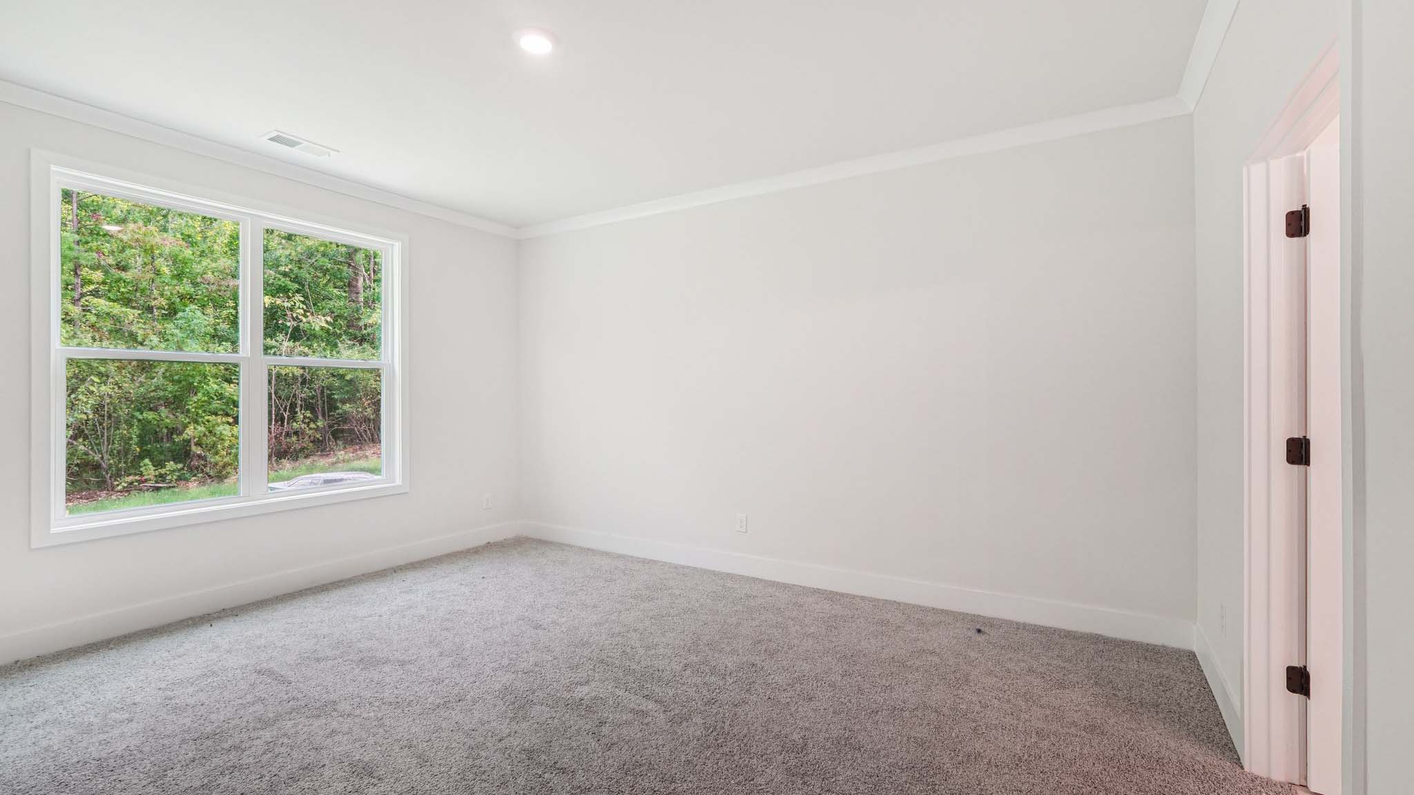 Primary carpeted bedroom with large windows