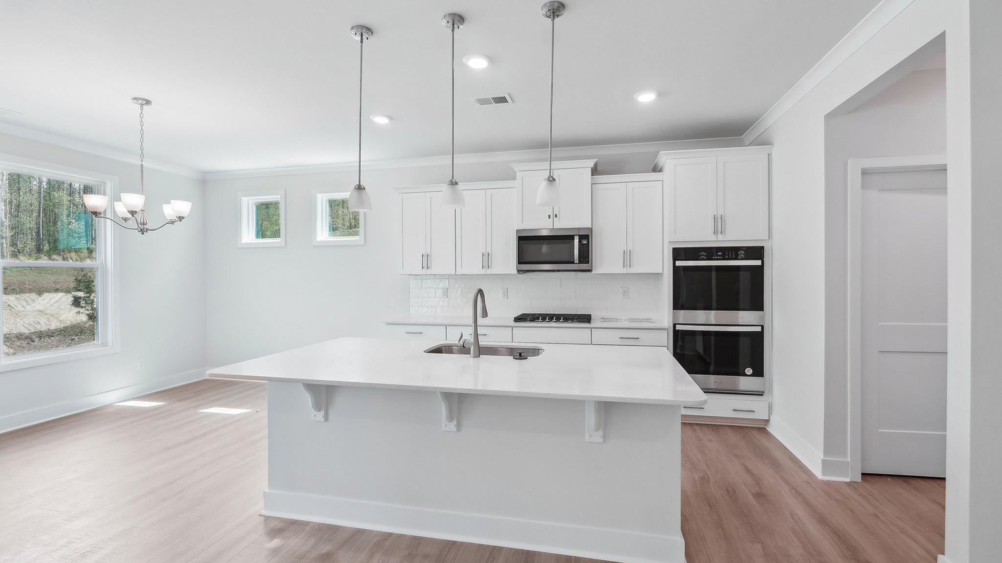 Kitchen and island with hanging lights, subway tile backsplash, and stainless steel appliances