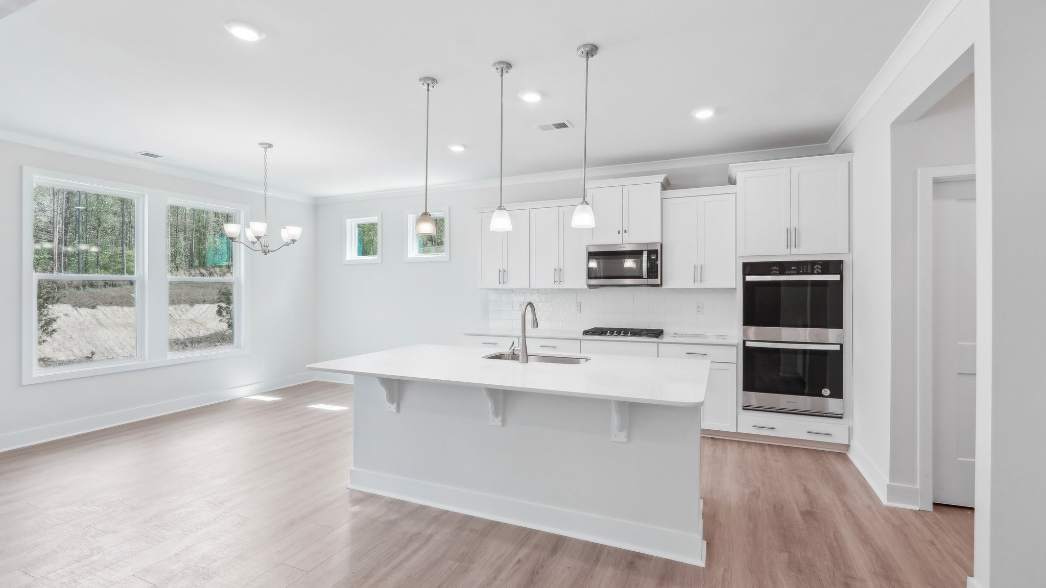 Kitchen and island with hanging lights, subway tile backsplash, and stainless steel appliances