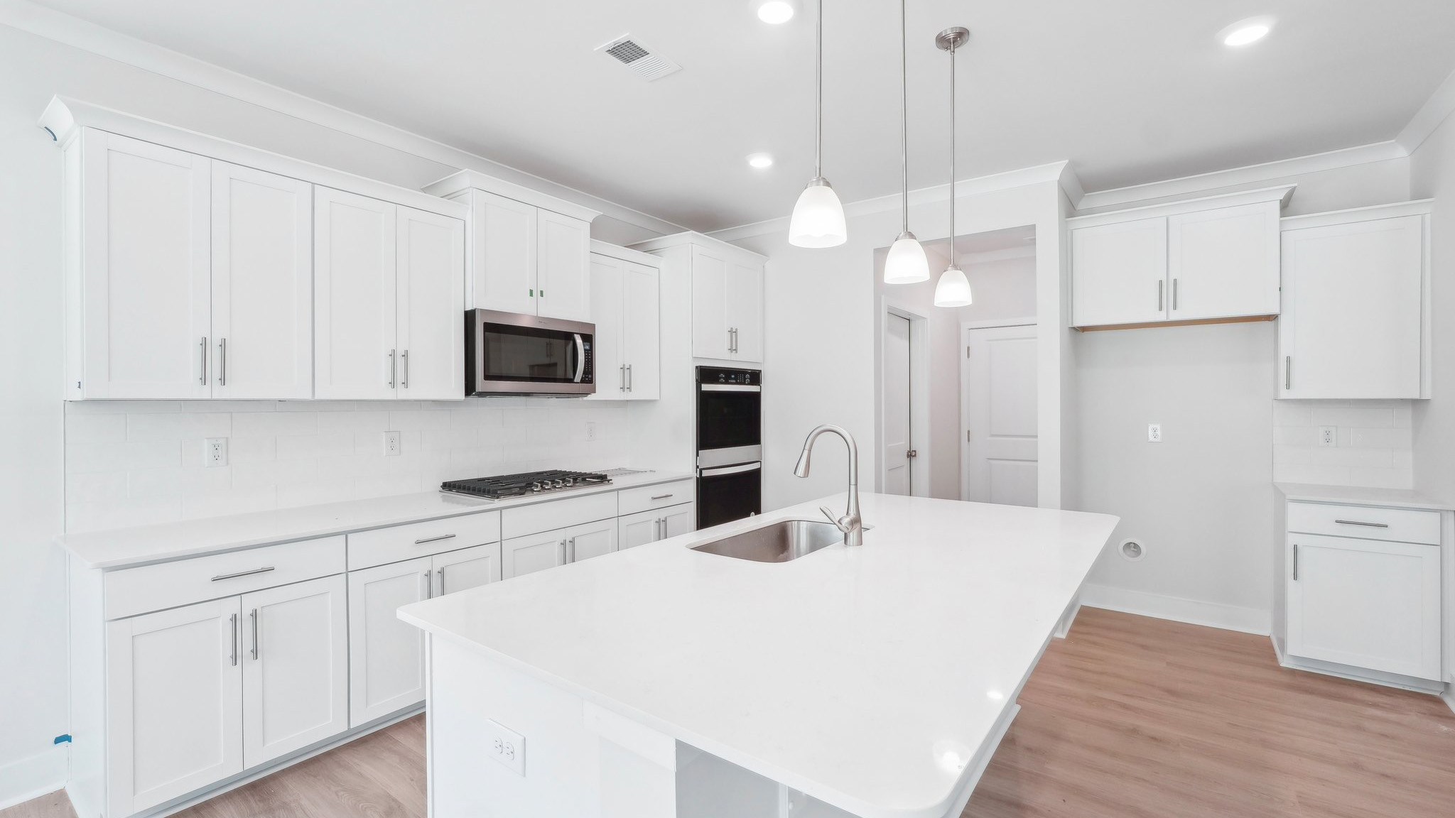 Kitchen and island with hanging lights, subway tile backsplash, and stainless steel appliances
