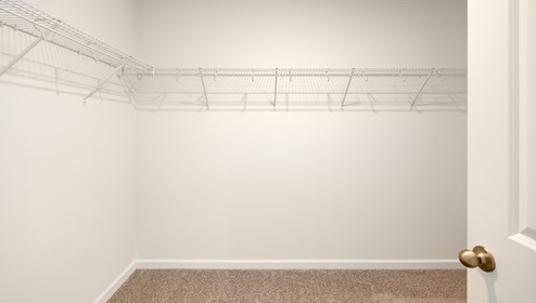 Carpeted walk in closet with hanging racks