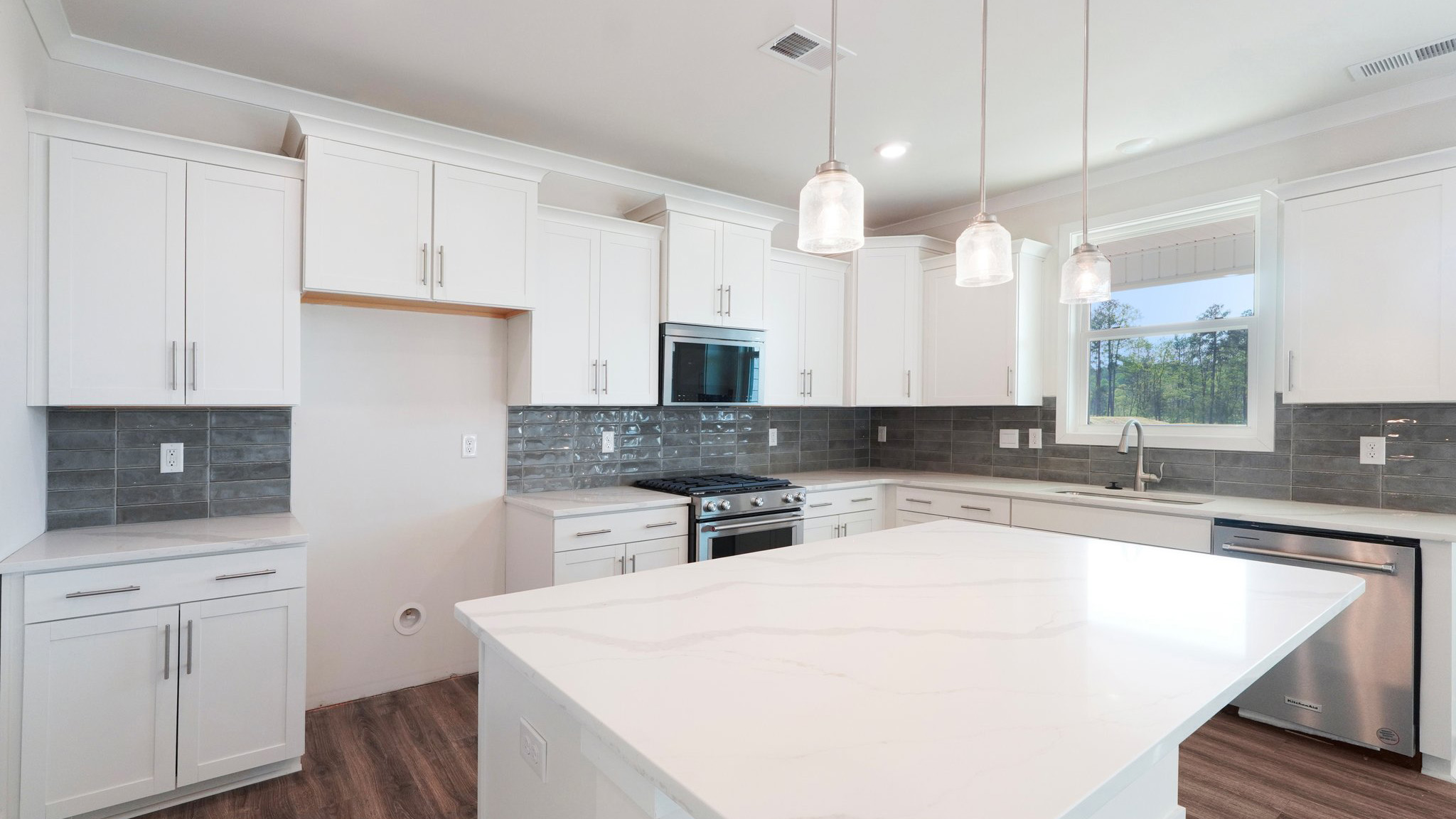 Kitchen and island with tile backsplash, white cabinets, and stainless steel backsplash