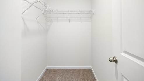 Carpeted walk in closet with hanging racks