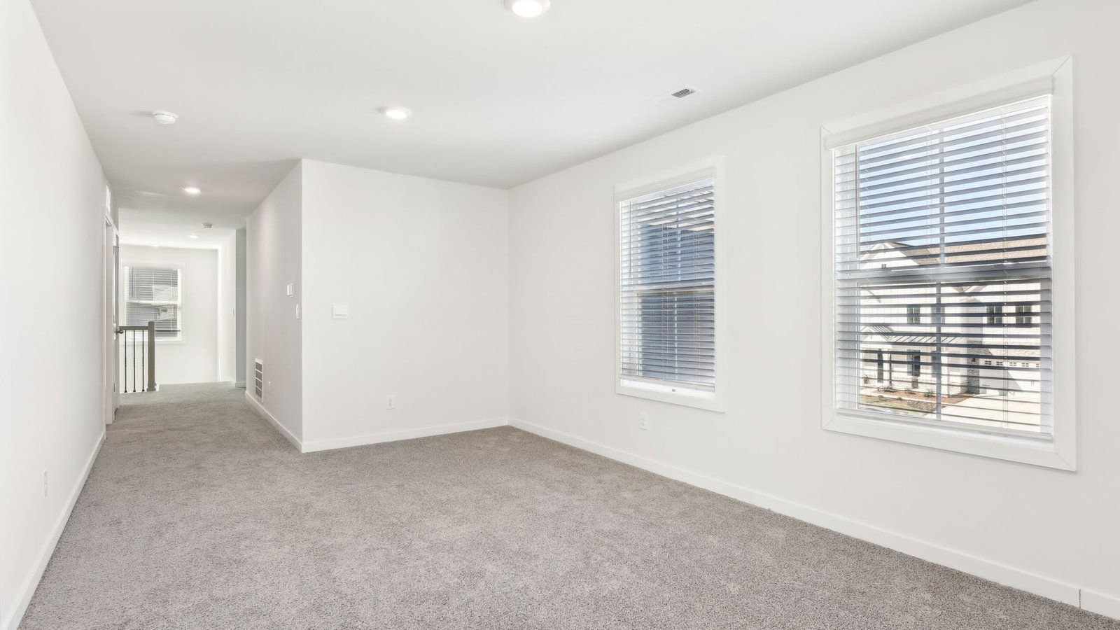 carpeted bedroom with two large windows
