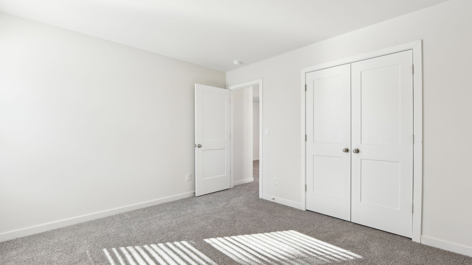 carpeted bedroom with two large windows