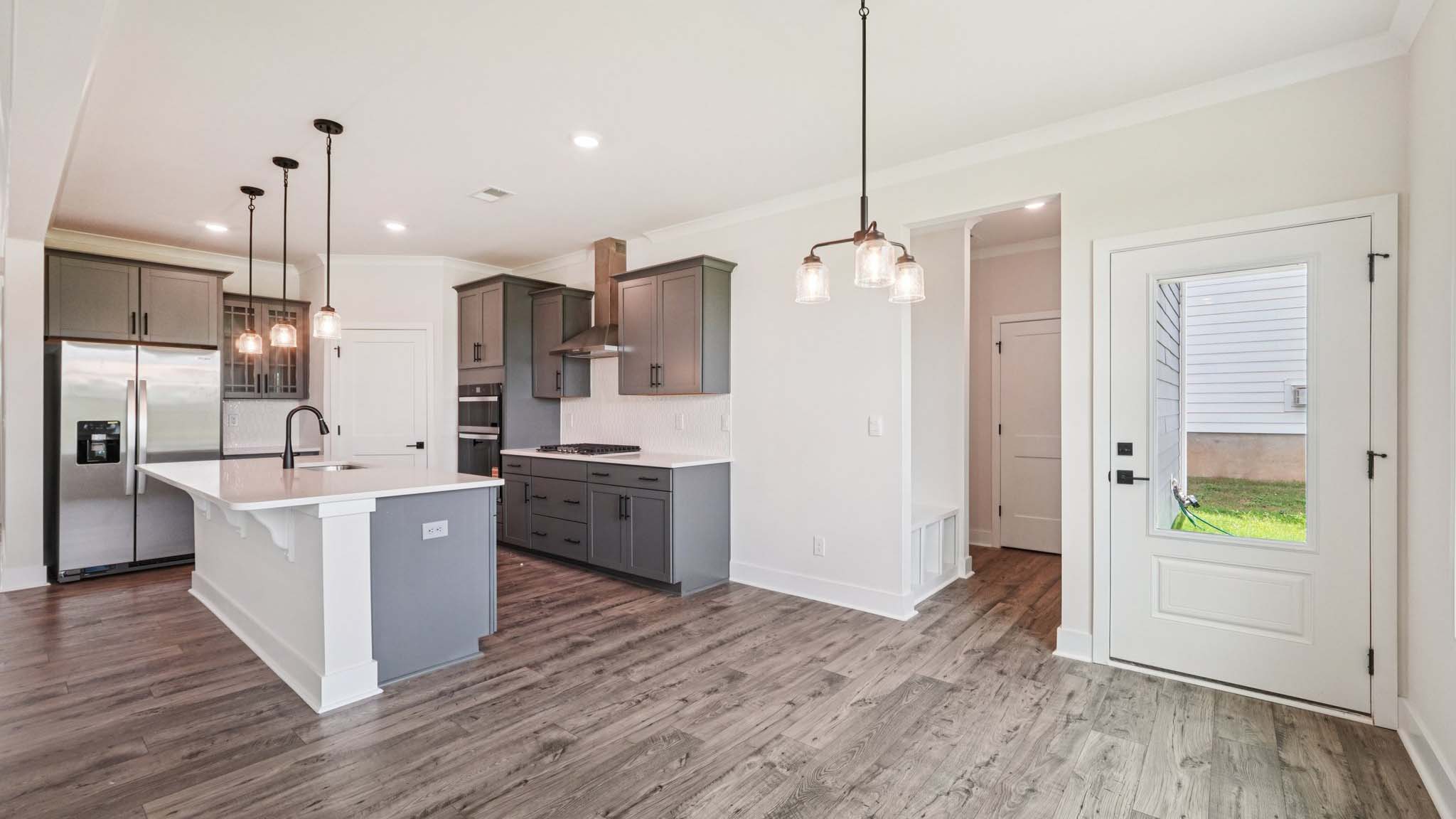 Open concept kitchen with gray cabinets, white countertops and stainless steel appliances