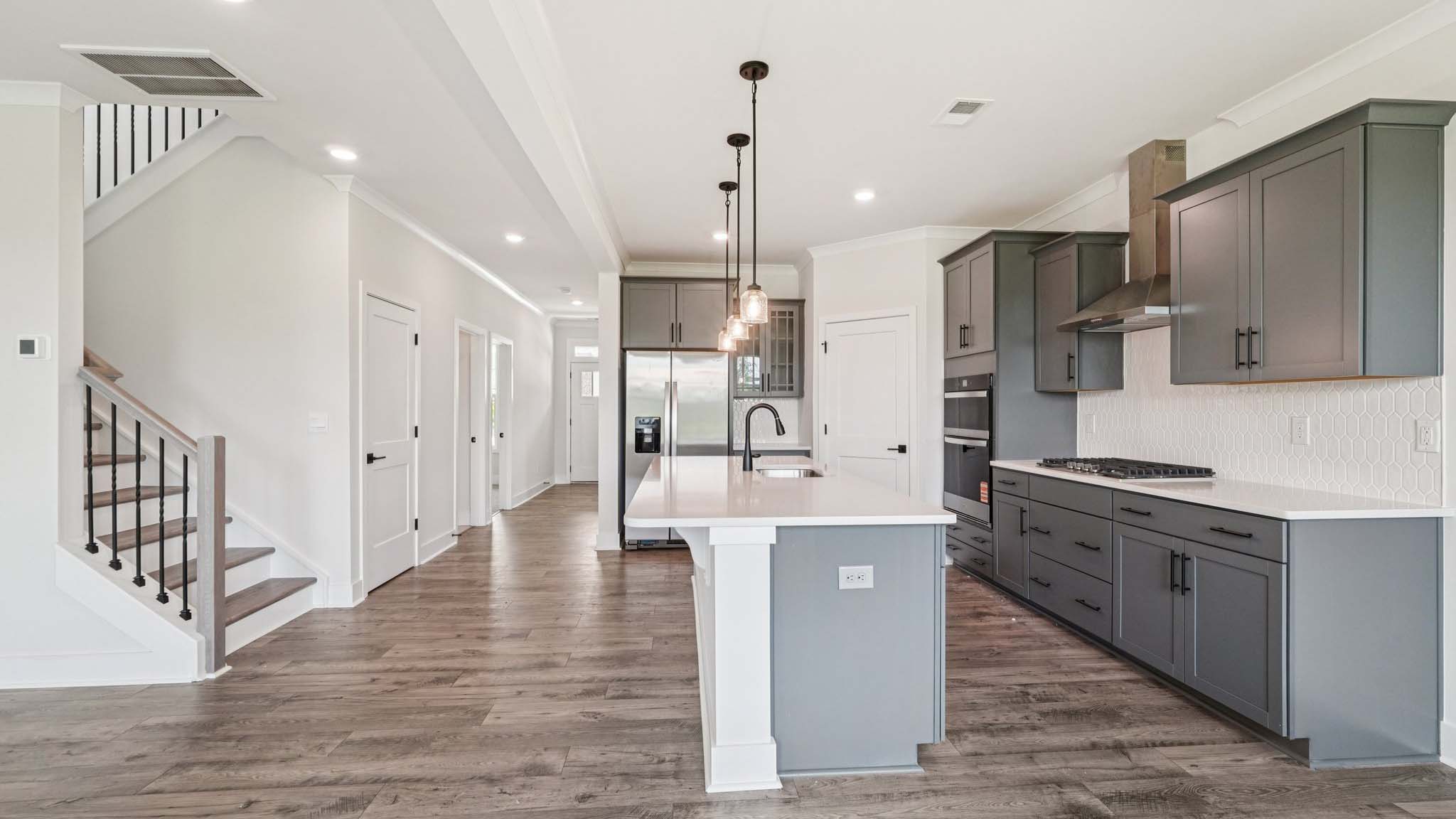 Open concept kitchen with gray cabinets, white countertops and stainless steel appliances