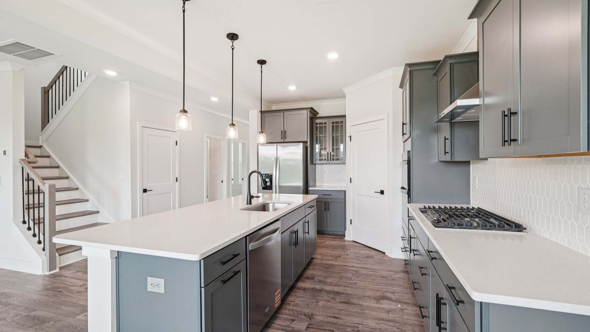 Open concept kitchen with gray cabinets, white countertops and stainless steel appliances