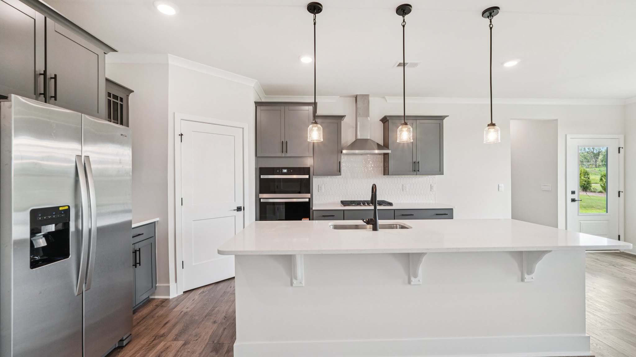 Open concept kitchen with gray cabinets, white countertops and stainless steel appliances